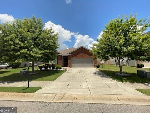 view of front of house with concrete driveway, a front lawn, an attached garage, and brick siding