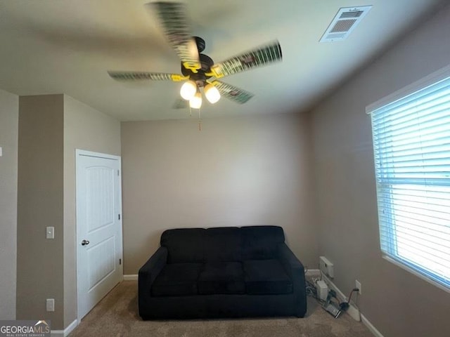 living area featuring ceiling fan, carpet flooring, visible vents, and baseboards