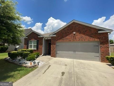 single story home with a garage, driveway, and brick siding