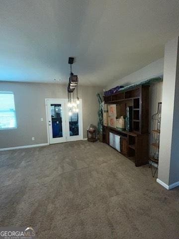 unfurnished living room featuring carpet floors and baseboards