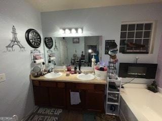 bathroom with a tub, a fireplace, a sink, and double vanity