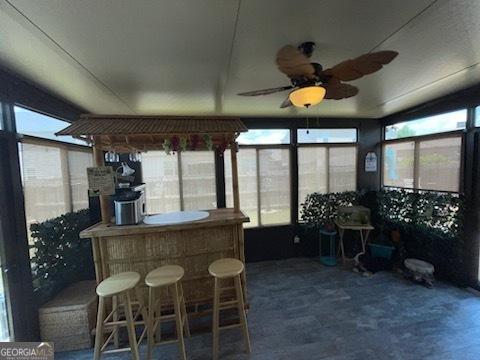 sunroom with a dry bar and a ceiling fan