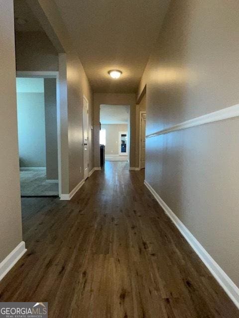 corridor with dark wood finished floors and baseboards