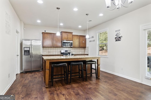 kitchen featuring decorative backsplash, appliances with stainless steel finishes, brown cabinets, dark wood-style flooring, and a sink