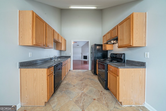 kitchen with dark countertops, under cabinet range hood, a high ceiling, black appliances, and a sink