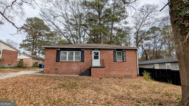 bungalow-style home with brick siding, crawl space, a front lawn, and fence