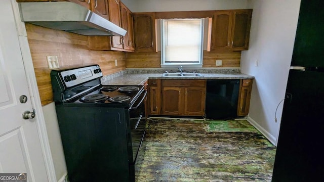 kitchen featuring brown cabinets, a sink, under cabinet range hood, and black appliances