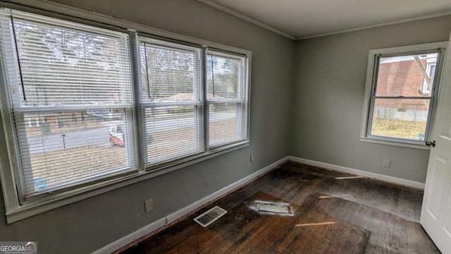 unfurnished room featuring visible vents, crown molding, baseboards, and wood finished floors