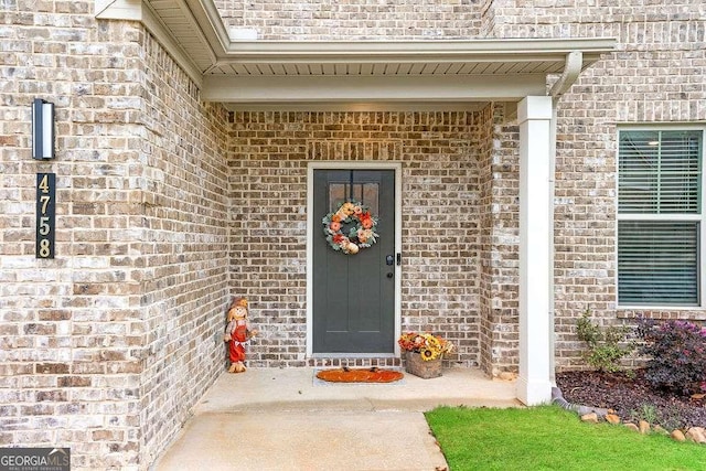 property entrance featuring brick siding and roof with shingles