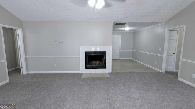 unfurnished living room with visible vents, a tiled fireplace, vaulted ceiling, a textured ceiling, and carpet floors