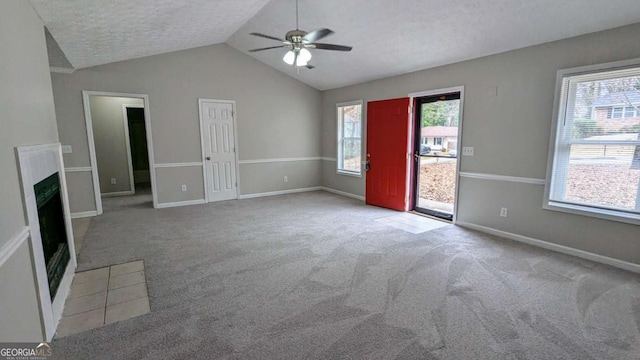 unfurnished living room with a fireplace with flush hearth, carpet, plenty of natural light, and a textured ceiling