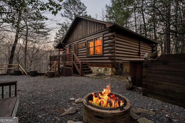 view of property exterior featuring log exterior, an outdoor fire pit, and board and batten siding