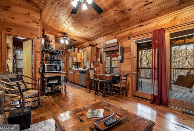 living room featuring wooden ceiling, light wood-style flooring, visible vents, and wood walls