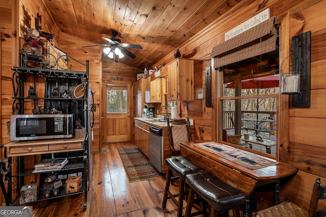 kitchen with wooden ceiling, wooden walls, appliances with stainless steel finishes, and vaulted ceiling