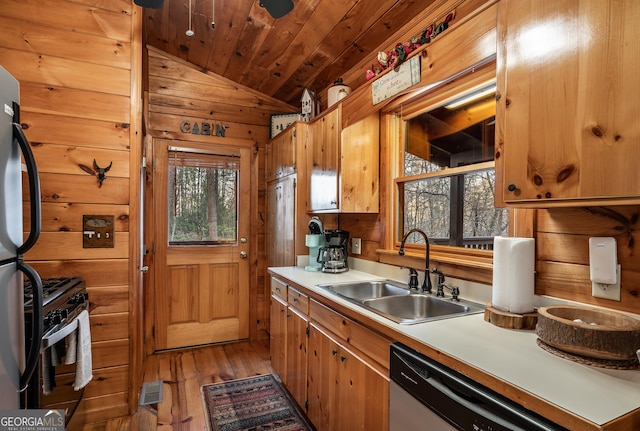 kitchen featuring wooden walls, wood ceiling, a wealth of natural light, appliances with stainless steel finishes, and a sink