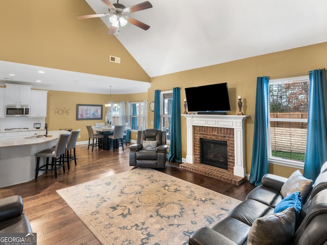 living room with ceiling fan, a fireplace, visible vents, baseboards, and dark wood-style floors