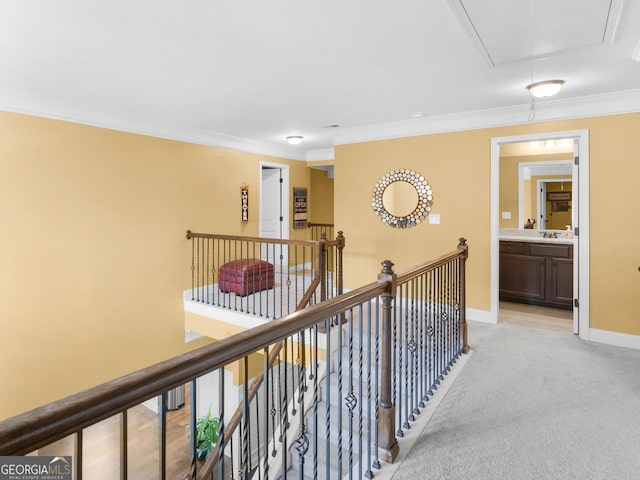 hall with attic access, ornamental molding, light carpet, an upstairs landing, and baseboards