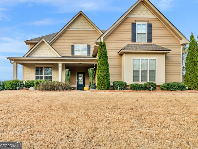 craftsman-style house with a front lawn, roof with shingles, and a porch