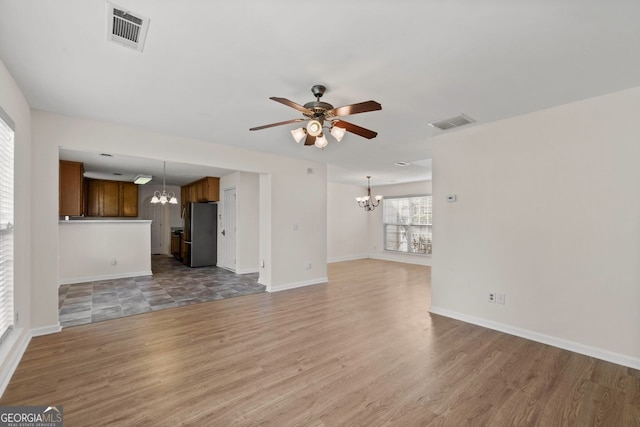 unfurnished living room with visible vents, light wood finished floors, and ceiling fan with notable chandelier