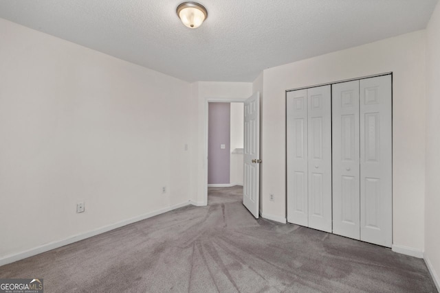 unfurnished bedroom with a textured ceiling, a closet, carpet, and baseboards