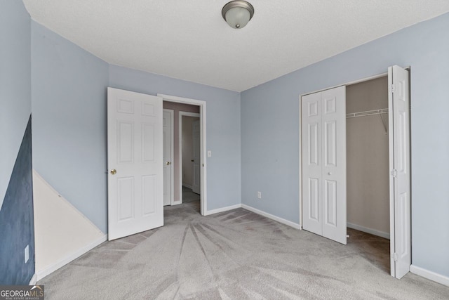 unfurnished bedroom featuring carpet floors, a textured ceiling, baseboards, and a closet