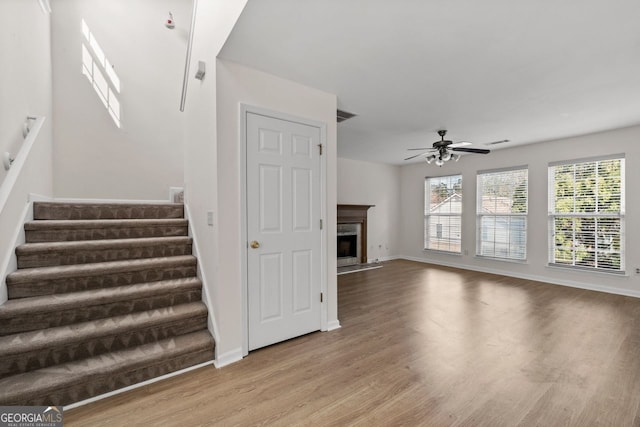 stairs with visible vents, a ceiling fan, a high end fireplace, wood finished floors, and baseboards