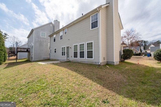 back of property featuring a patio area, a chimney, and a lawn