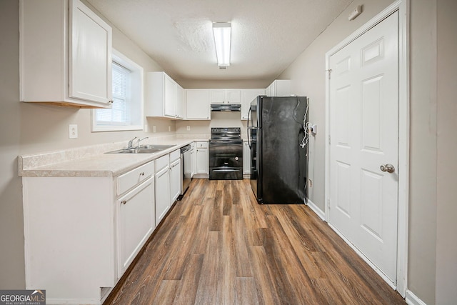 kitchen featuring a textured ceiling, dark wood-style flooring, white cabinetry, range hood, and black appliances