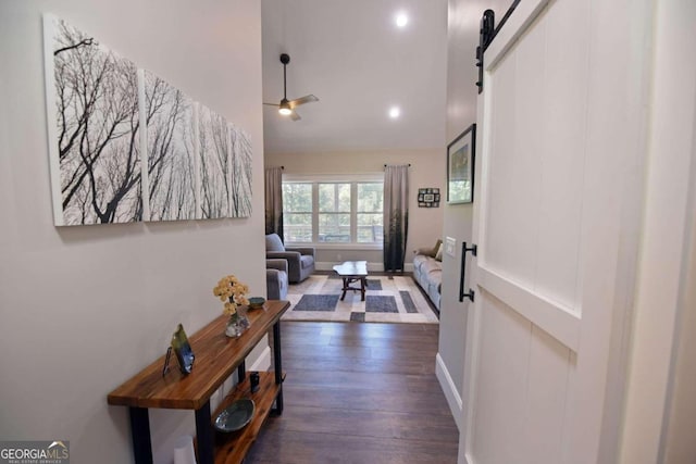 hallway with vaulted ceiling, a barn door, dark wood-type flooring, and baseboards