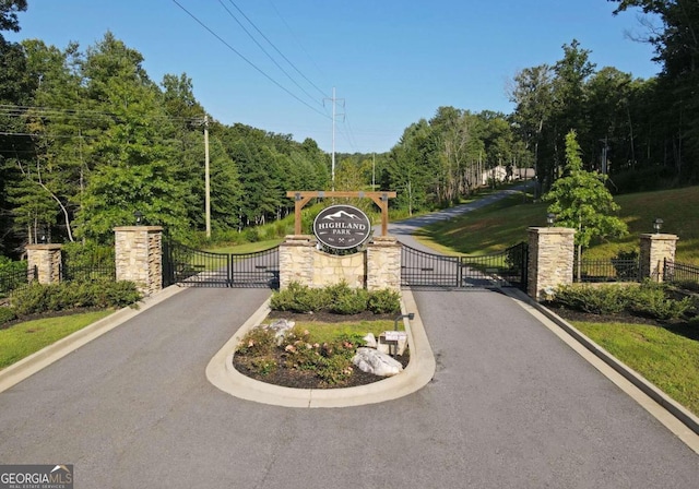 view of road featuring a gate, a gated entry, and curbs