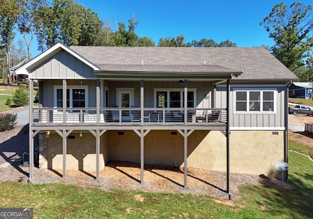 back of house featuring central AC, roof with shingles, board and batten siding, and a wooden deck