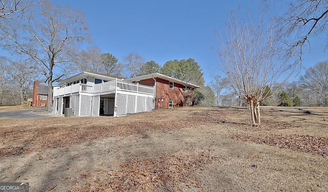 view of side of home featuring brick siding and a wooden deck