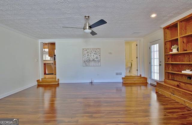 unfurnished living room featuring dark wood-style floors, crown molding, visible vents, a textured ceiling, and baseboards