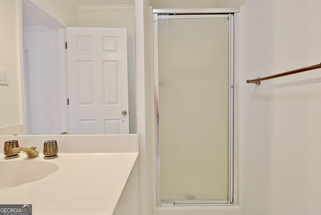 bathroom with crown molding, a sink, and a shower stall