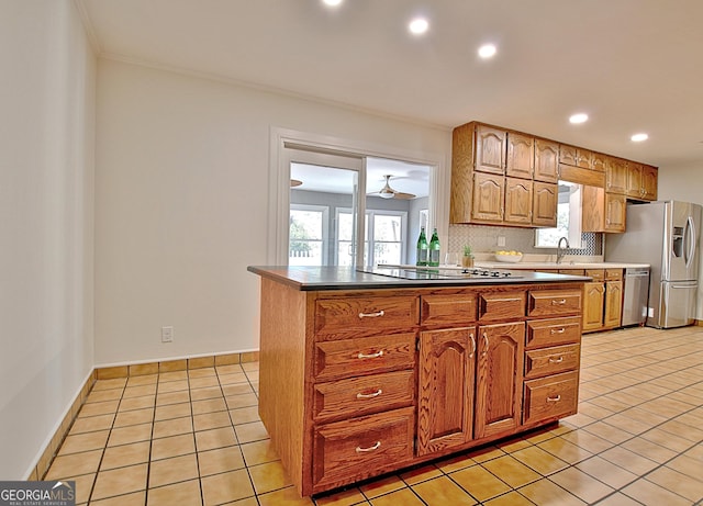 kitchen with light tile patterned floors, stainless steel appliances, baseboards, decorative backsplash, and brown cabinetry