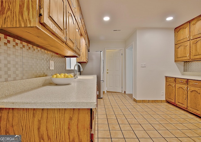 kitchen with light tile patterned floors, backsplash, light countertops, and a sink