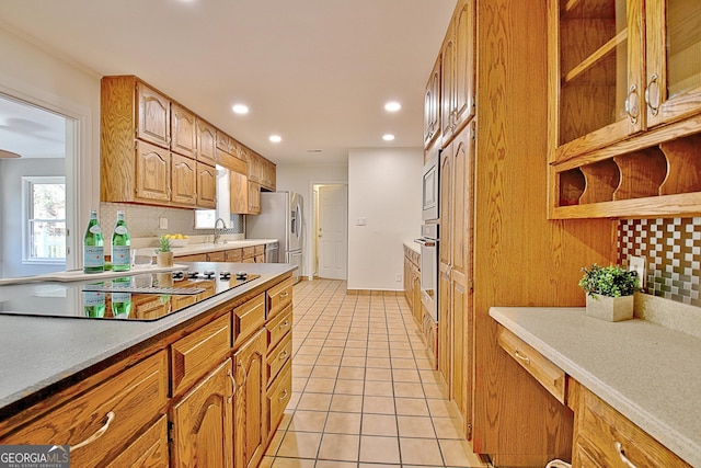 kitchen featuring light tile patterned floors, light countertops, decorative backsplash, appliances with stainless steel finishes, and a sink