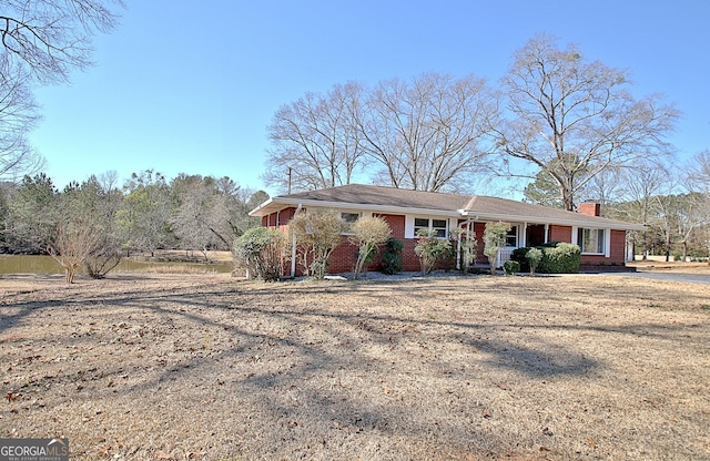 ranch-style house featuring a chimney and brick siding