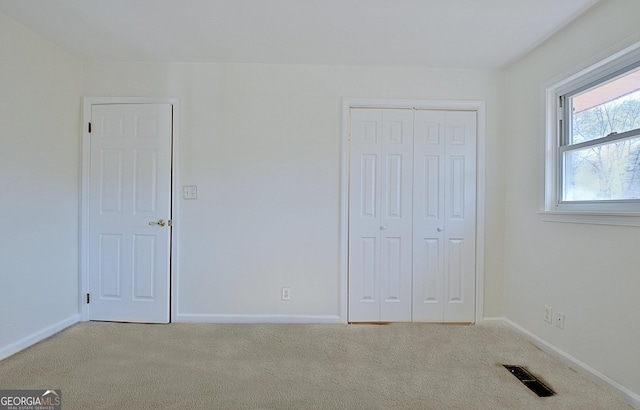 unfurnished bedroom featuring a closet, carpet, visible vents, and baseboards