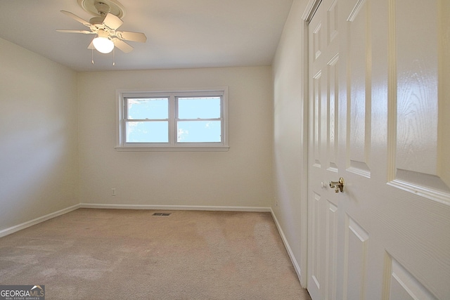 empty room with light carpet, ceiling fan, visible vents, and baseboards