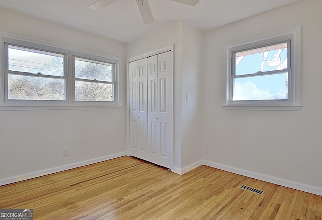 unfurnished bedroom with baseboards, multiple windows, visible vents, and wood finished floors