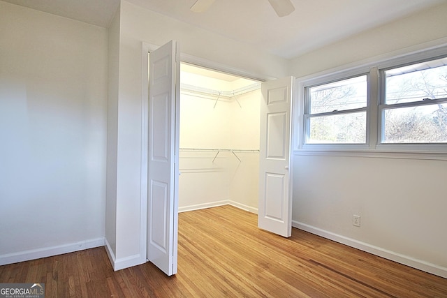 unfurnished bedroom with ceiling fan, a closet, baseboards, and wood finished floors