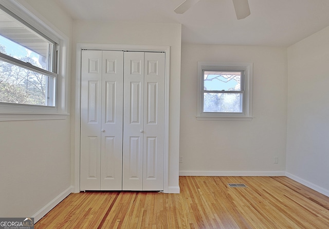 unfurnished bedroom with light wood finished floors, multiple windows, and visible vents