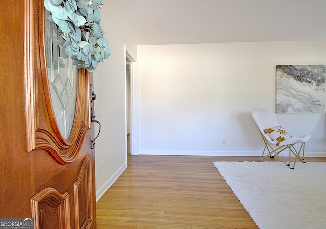 corridor with light wood-type flooring and baseboards