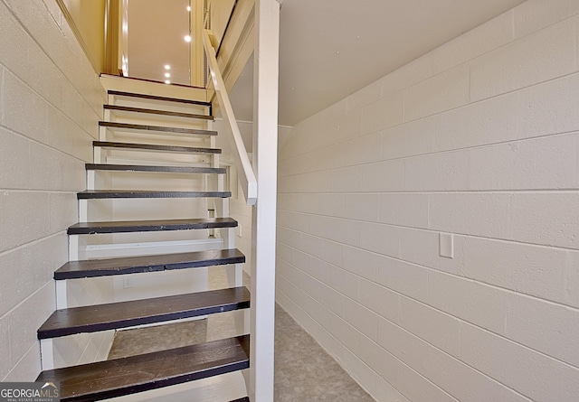 staircase featuring concrete block wall