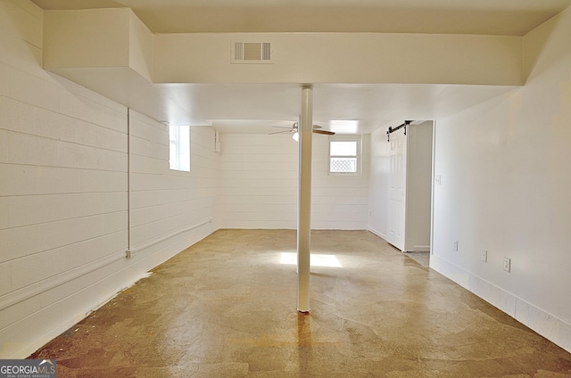 below grade area with a barn door, visible vents, and a ceiling fan