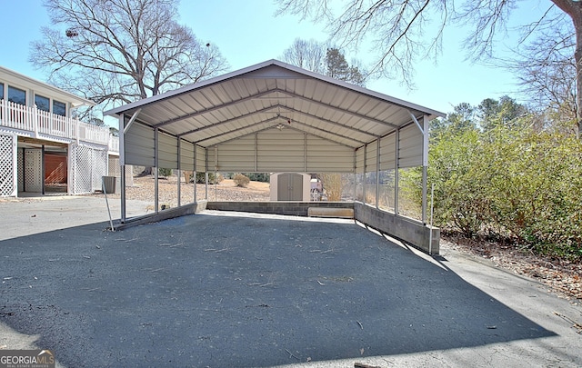 view of parking / parking lot with driveway, a shed, and a carport