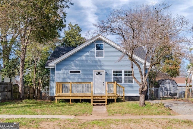 view of front of house featuring a front lawn, fence, a wooden deck, and a gate