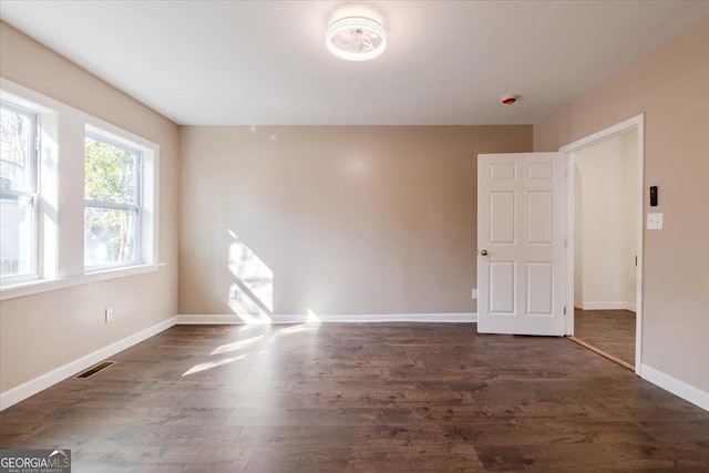 spare room with dark wood-style floors, baseboards, and visible vents