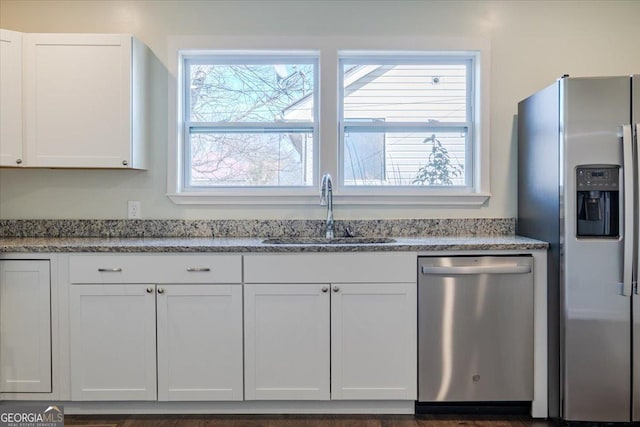 kitchen with stainless steel appliances, a wealth of natural light, a sink, and white cabinetry